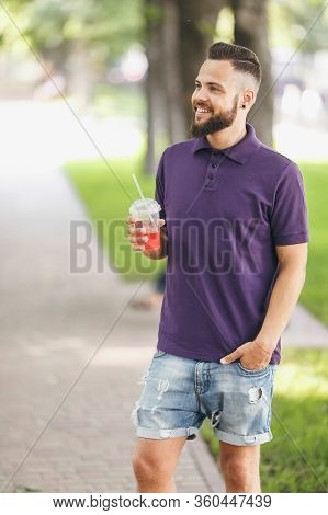 A Young Guy Walking In The Park With Lemonade In The Spring. Spring Day.