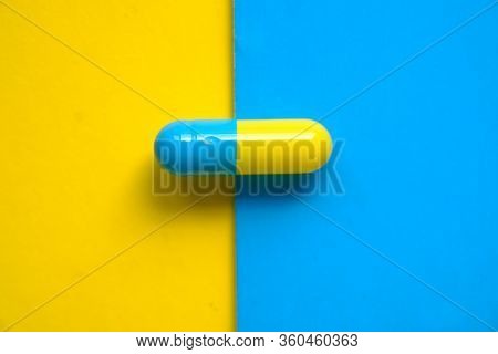 One Single Colorful Capsule On Yellow And Blue Background
