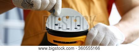 Close-up Of Carpenter Worker Changing Disc On Yellow Sander Machine. Construction Repairman In White