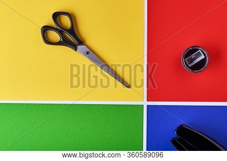 Multi-colored Paper Background. Yellow, Green, Red And Blue. On The Yellow Background There Are Scis