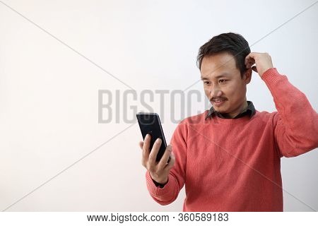A North East Indian Manipuri Guy Taking Selfie Photograph In A Mobile Phone Isolated In White Backgr