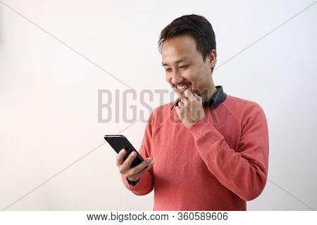 A Man Looking At His Phone In A Happy Mood Isolated In White Background With Space For Text