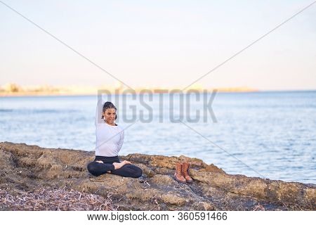 Young beautiful sportwoman practicing yoga. Coach stretching at the beac