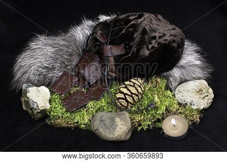 A Set Of 24 Brown Leather Norse Runes In A Bag On A Background Of Fur, Moss, Stones And A Candle.