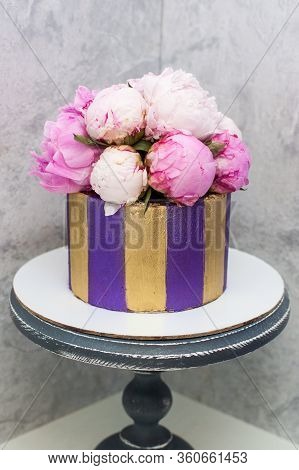 Modern, Elegant Violet And Golden Cake Decorated With Fresh Peony Flowers. Grey Background