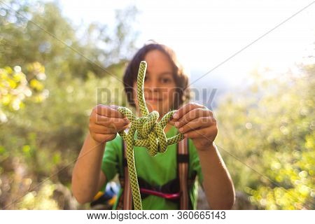 A Child Learns To Knit The Safety Knot From The Rope.