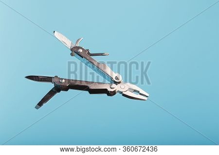 The Multitool Multi-function Tool Hovers On A Blue Background. The Concept Of An Expanded Multi-tool