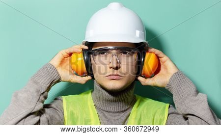 Portrait Of Young Construction Engineer Worker Wearing Safety Helmet, Goggles, Jacket And Headphones