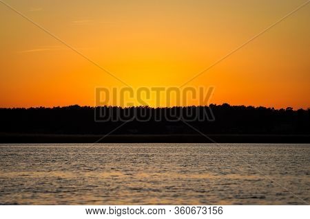 Late Evening River Sunset View With Small Waves On The Water And Orange-yellow Sky. Photo Taken In L