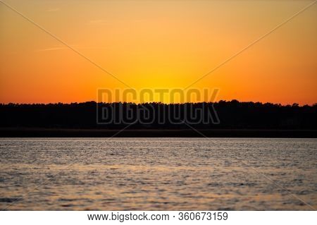 Late Evening River Sunset View With Small Waves On The Water And Orange-yellow Sky. Photo Taken In L