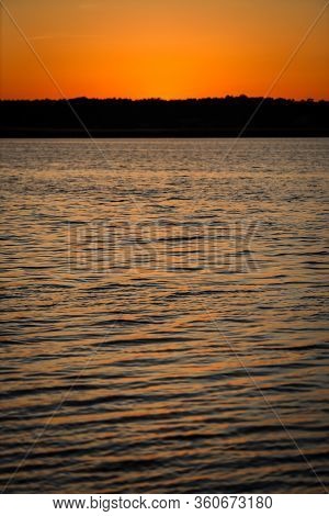 Late Evening River Sunset View With Small Waves On The Water And Orange-yellow Sky. Photo Taken In L