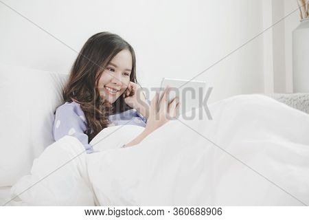 Social Distancing. Happy Young Asian Pretty Woman Video Call Chat On Digital Mobile Tablet On Bed At
