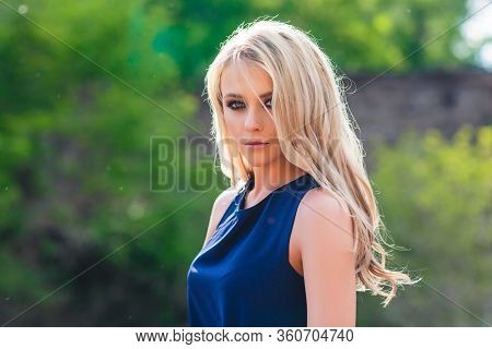 Young Beautiful Blond Woman In Blue Mini Dress And Floral Wreath Standing And Trying Water On Summer