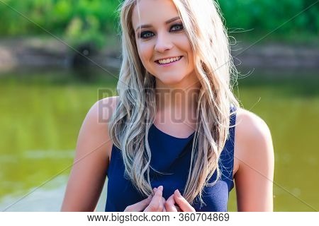 Young Beautiful Blond Woman In Blue Mini Dress And Floral Wreath Standing And Trying Water On Summer