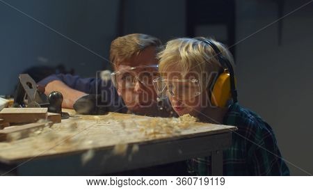 Father And Son Blow On Sawdust. Fun After Hard Work In The Garage