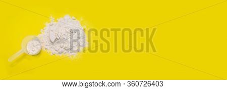 Pile Of Banana Protein Powder And Measuring Cup Isolated On Yellow Background