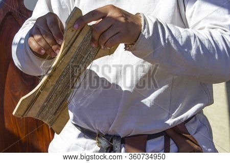 Man In National Costume Is Making Bowstring For  Bow,  Master Class On Craft.