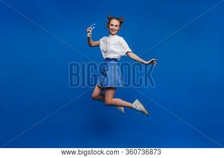 Happiness, Freedom, Movement And People Concept - Smiling Young Woman Jumping In The Air Over Blue B