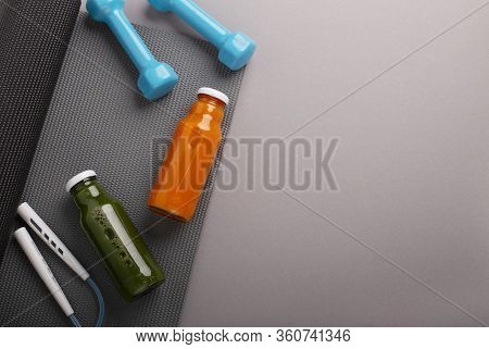 Sport At Home. Yoga Mat, Protein And Detox Bottles, Dumbbells And Jumping Rope On Gray Background. S