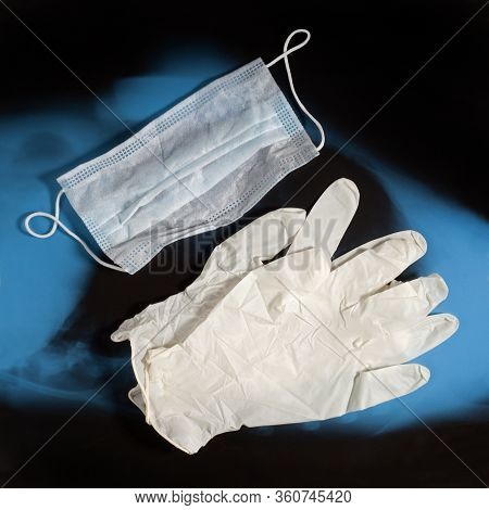 Pair Of Latex Medical Gloves And Ear-loop Mask On Blue Black X-ray Image Background. Protection Conc