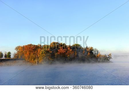 Morning Light Illumines Trees Lining The Shores Of Table Rock Lake In Branson, Missouri.  Mist Rises