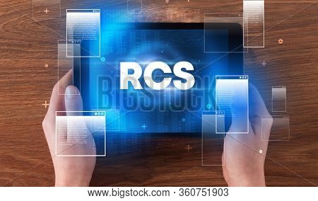 Close-up of a hand holding tablet with RCS abbreviation, modern technology concept