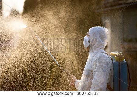 Man in protective equipment decontaminating and spraying on a public place as a prevention against Coronavirus disease 2019, COVID-19. Coronavirus pandemic.