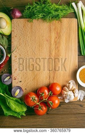 Wooden Board With Clear Space. Around Tomato And Dill, Olive Oil, Peper, Avocado, Green Onion, Spina