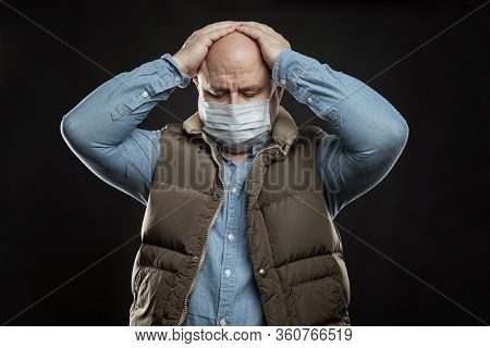 Sad Bald Adult Man In A Medical Mask Stands Holding His Head With His Hands. Precautions Quarantined