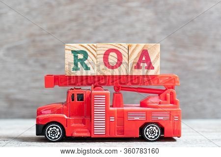 Red Fire Truck Hold Letter Block In Word Roa (abbbreviation Of Return On Assets) On Wood Background