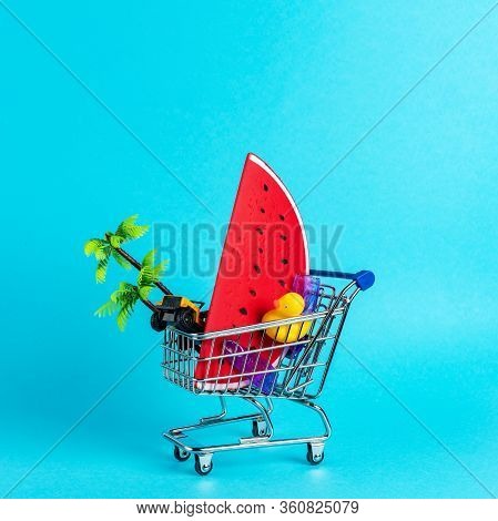Tropical Beach Concept Made With Summer Things In Shopping Troley On Blue Background. Creative Minim
