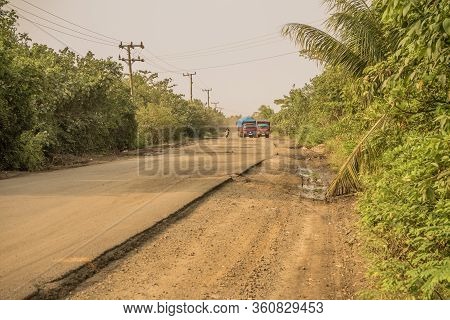 Motorcycle Overtaking Old Trucks Loaded With Sawit Palms Seen On A Dusty Bumpy Road Near To Bengkulu