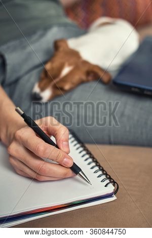 Woman Write Plans In The Notebook With Her Jack Rusel Terrier Puppy Dog. Good Relationships And Frie