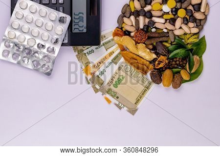 Top View Of Natural Medicines, Money, Calculator, Pills And Different Spices With Green Leaves On Wh