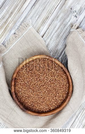 Raw Roasted Buckwheats In Round Wooden Bowl On Light Wood. Russian Grechka. Organic Healthy Diet Foo
