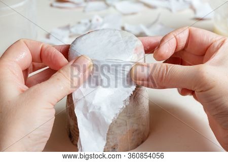 Female Hands Glue A Glass With Scraps Of Paper In The Process Of Creating Paper Mache