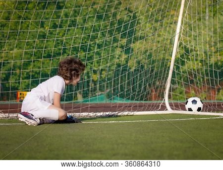 Junior Soccer Goalkeeper. Disappointed Boy In White Goalie Sportswear. Goalkeeper Missed A Goal Duri