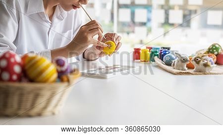 Happy Asian Woman Painting Eggs For Eastertime At Home. Family Preparing For Easter.