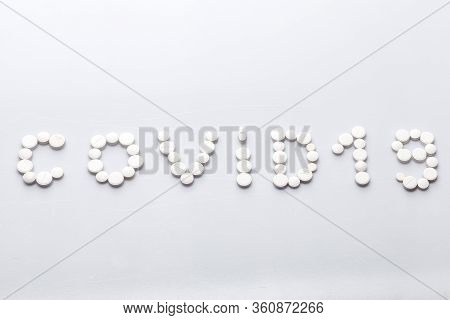 Covid-19 Inscription Made Of Round White Tablets On A White Background, Medical Concept On The Theme