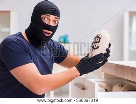 Robber wearing balaclava stealing valuable things