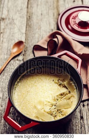 Creamy Polenta With Baked Onion And Cheese In Cast Iron Pot On Rustic Wooden Background. Italian Foo