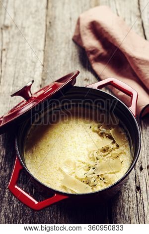 Creamy Polenta With Baked Onion And Cheese In Cast Iron Pot On Rustic Wooden Background. Italian Foo