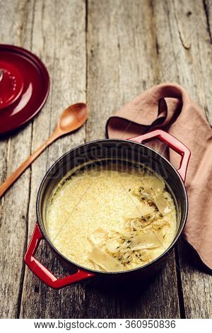 Creamy Polenta With Baked Onion And Cheese In Cast Iron Pot On Rustic Wooden Background. Italian Foo