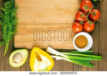 Wooden Board With Clear Space. Around Tomato And Dill, Olive Oil, Peper, Avocado, Green Onion, Spina