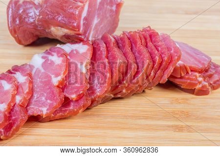 Sliced Air-cured And Smoked Pork Neck Against The Unsliced Rest Of The Piece On The Bamboo Wooden Cu