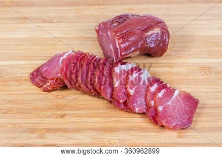 Sliced Air-cured And Smoked Pork Neck And Unsliced Rest Of The Piece On The Bamboo Wooden Cutting Bo