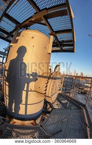 The Shadow Of An Engineer In A Hard Hat And Overalls Falls On A New Hydrocracking Column