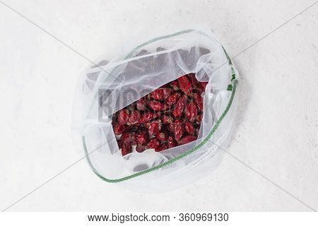 Dried Rose Hips In Mesh Bag On White Background