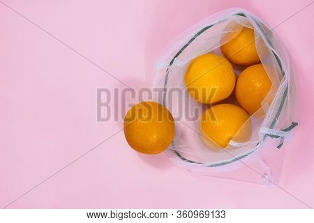 Oranges In Mesh Bag Flat Lay On Pink Background