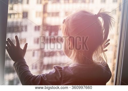 Girl Looks Lonely Through Window By Putting Her Hands On Window Sill